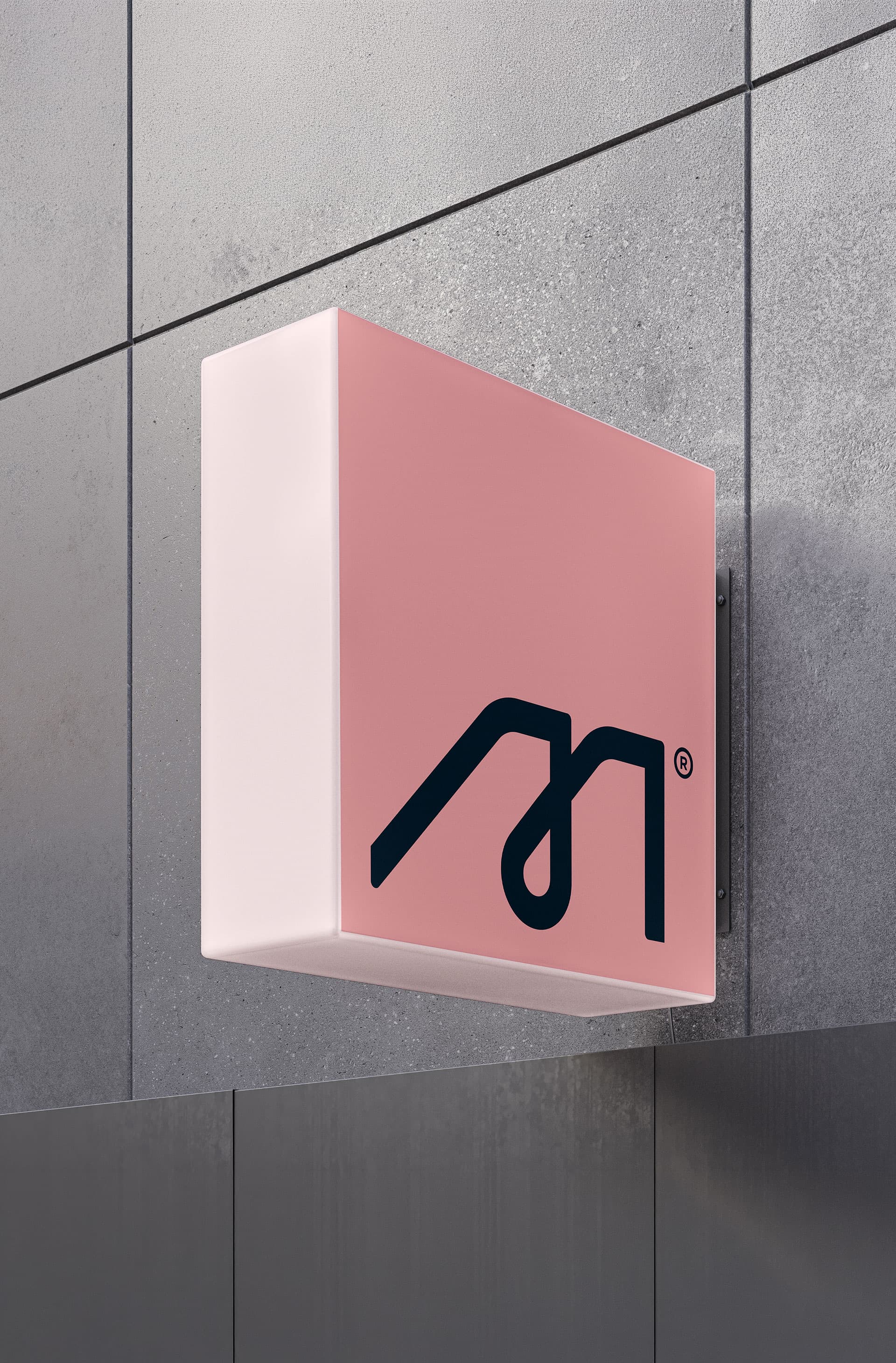 Susana Méndez. Illuminated exterior signage with the M mark, mounted on a concrete facade.