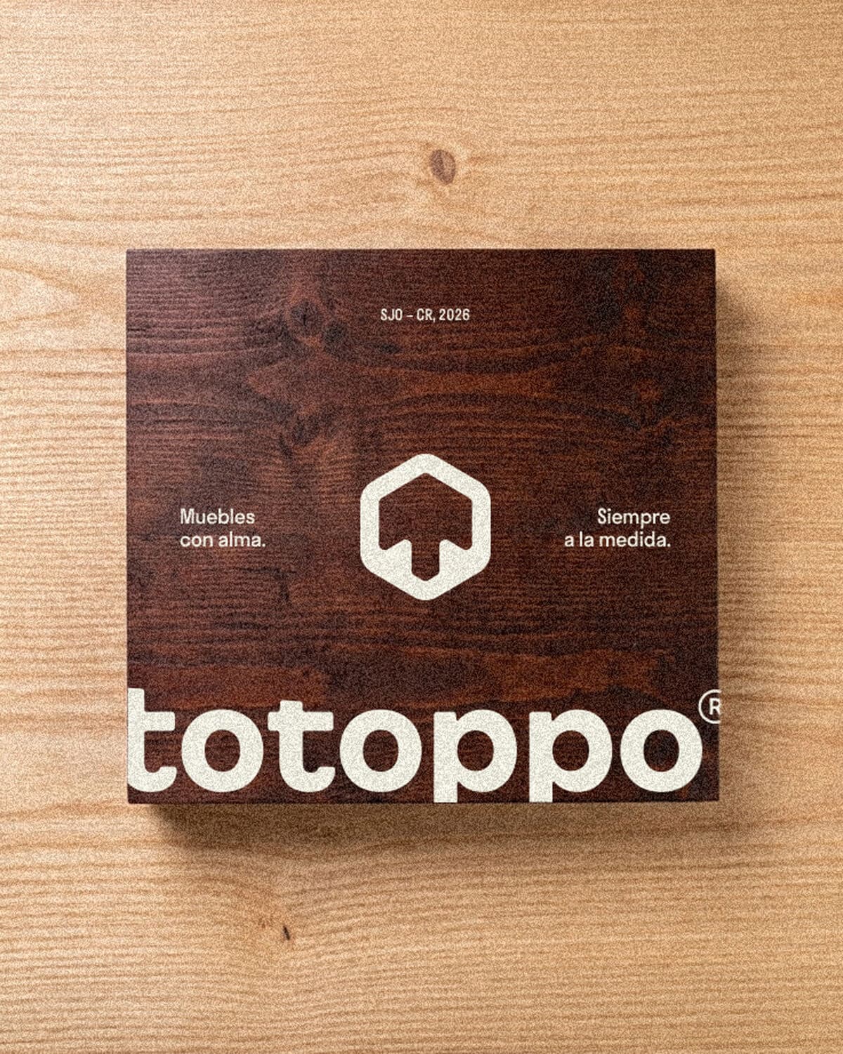 Totoppo. A cover card mockup with the wordmark and house mark, on a wood surface.